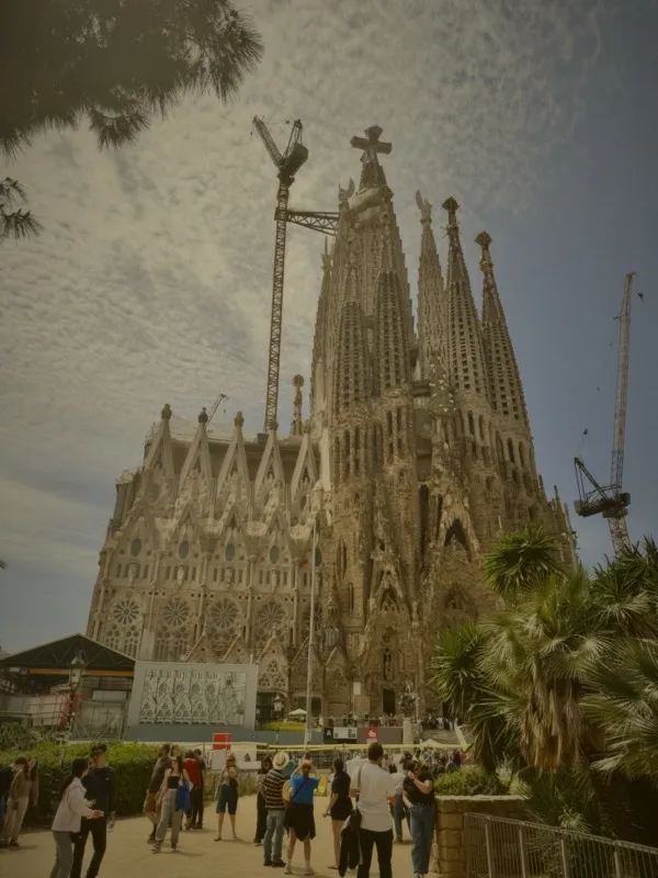 Sagrada Familia full facade with palm trees and visitors