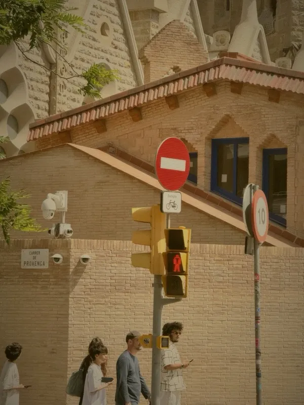 Pedestrians at a terracotta street corner near Sagrada Familia